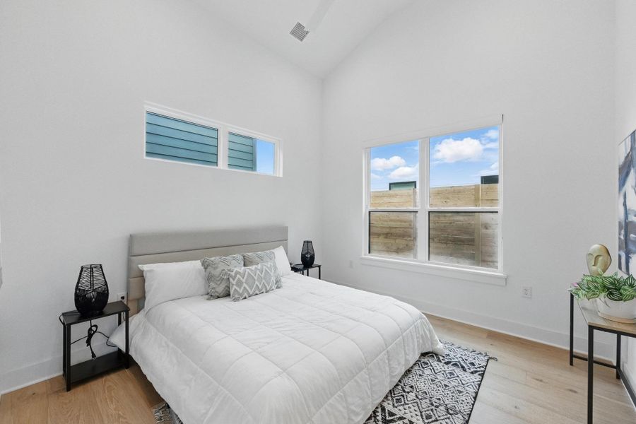 Bedroom featuring light wood-style flooring and high vaulted ceiling Bedroom featuring light wood-style flooring and high vaulted ceiling
