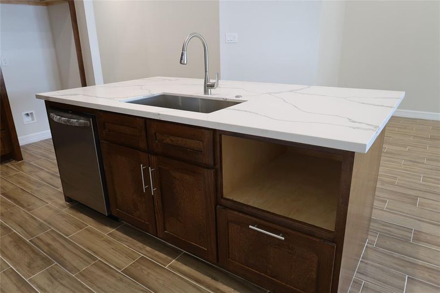 Oversized island with stainless steel sink and dishwasher.