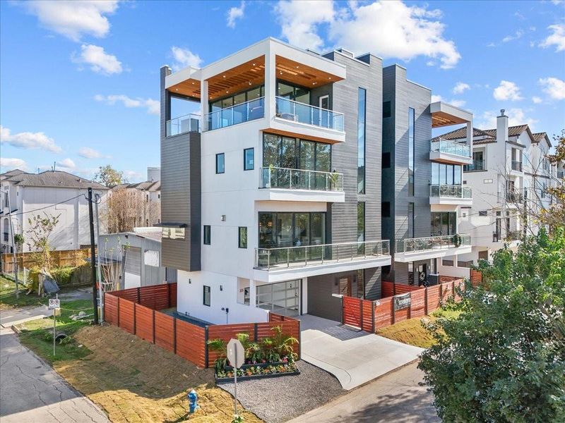 Modern three-story home with sleek design, featuring large glass balconies and wood accents. Located on a corner lot, it offers a fenced yard and driveway parking in a vibrant neighborhood. Modern three-story home with sleek design, featuring large glass balconies and wood accents. Located on a corner lot, it offers a fenced yard and driveway parking in a vibrant neighborhood.