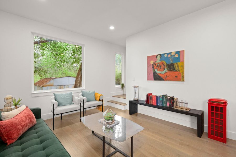 Bright living area featuring light wood-finish flooring, recessed lighting, and a large picture window