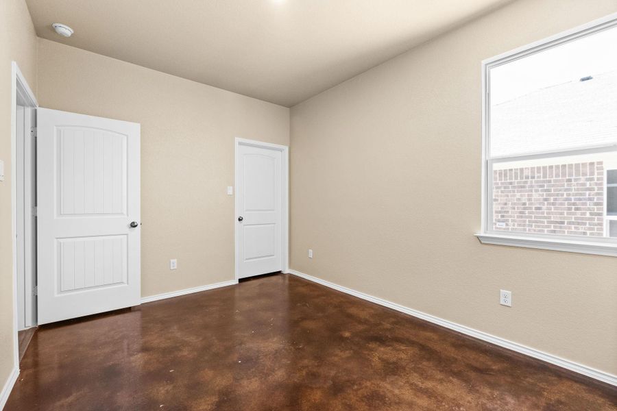 Unfurnished bedroom featuring finished concrete flooring and baseboards