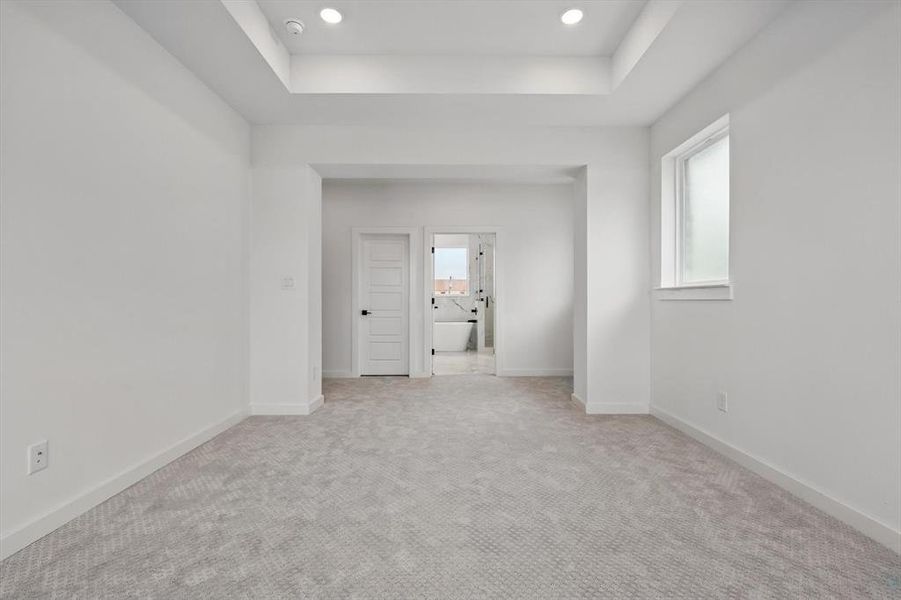 Spare room with a raised ceiling, light carpet, baseboards, recessed lighting, and a smoke detector