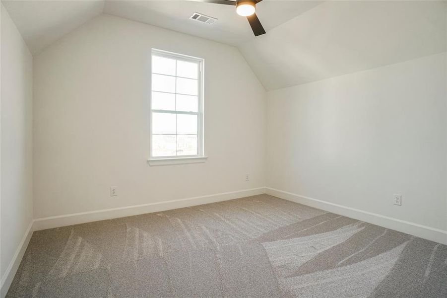 Additional living space with vaulted ceiling, light carpet, and ceiling fan