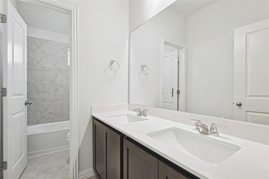 Bathroom with double vanity, light tile patterned floors, and shower / washtub combination Bathroom with double vanity, light tile patterned floors, and shower / washtub combination