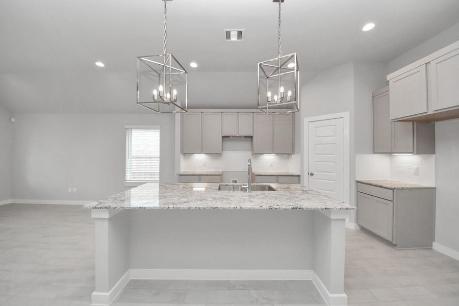 The kitchen is a culinary haven, featuring granite countertops, a tile backsplash, stainless steel appliances, 42” upper cabinets, and undercabinet lighting.