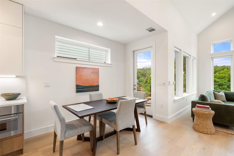 An inviting dining area offers a bright, open floorplan with views of verdant trees from oversized windows. An inviting dining area offers a bright, open floorplan with views of verdant trees from oversized windows.