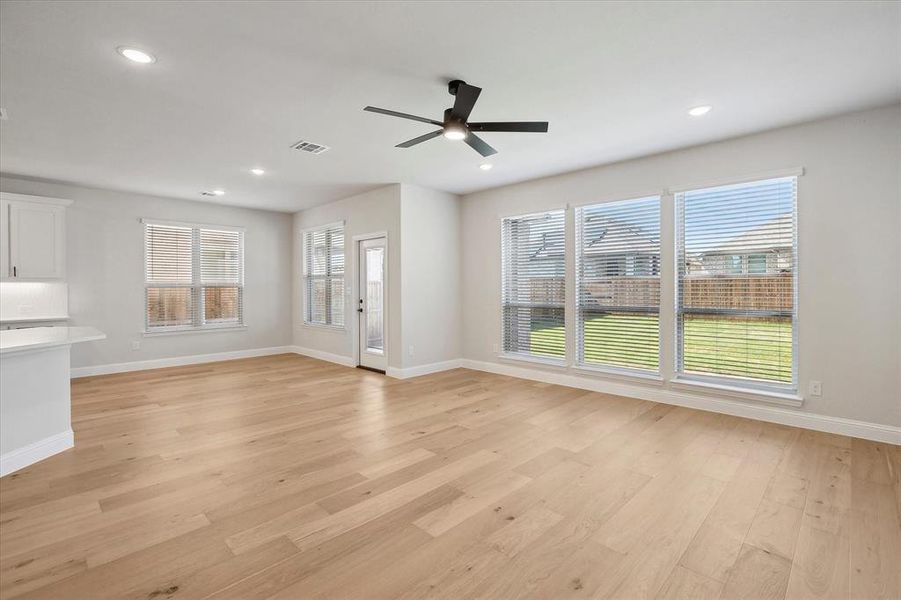 Unfurnished living room with ceiling fan, light wood-style flooring, baseboards, and recessed lighting