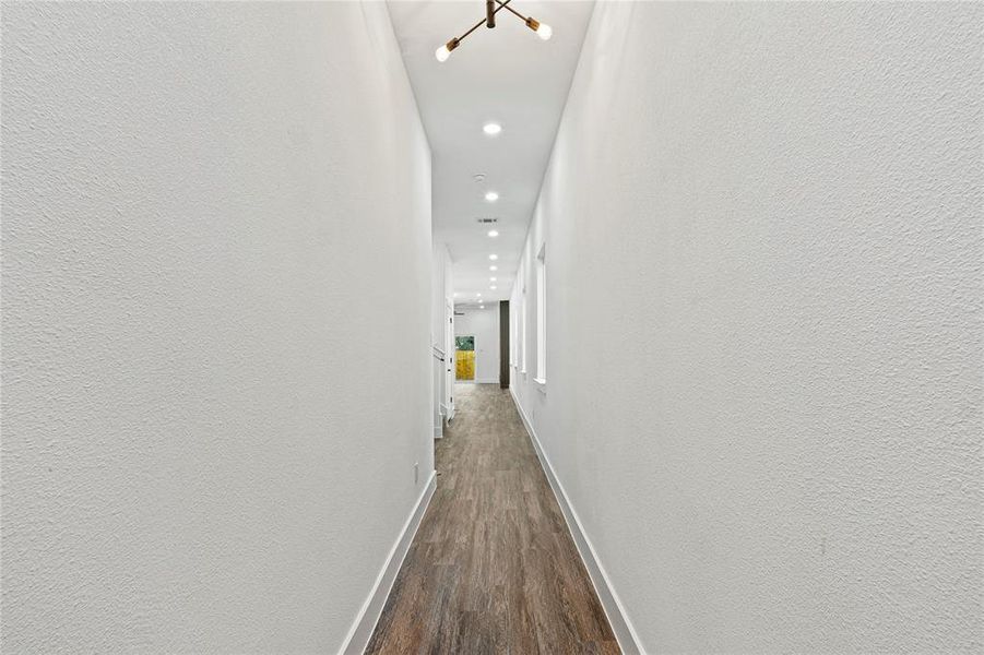Hall featuring recessed lighting, dark wood-style flooring, and a textured wall Hall featuring recessed lighting, dark wood-style flooring, and a textured wall
