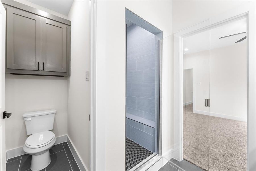 Bathroom featuring a shower stall and dark tile patterned flooring Bathroom featuring a shower stall and dark tile patterned flooring
