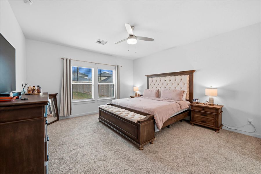 A serene primary suite features soft, plush carpeting and expansive windows that fill the space with natural light, offering a peaceful, private escape. A serene primary suite features soft, plush carpeting and expansive windows that fill the space with natural light, offering a peaceful, private escape.