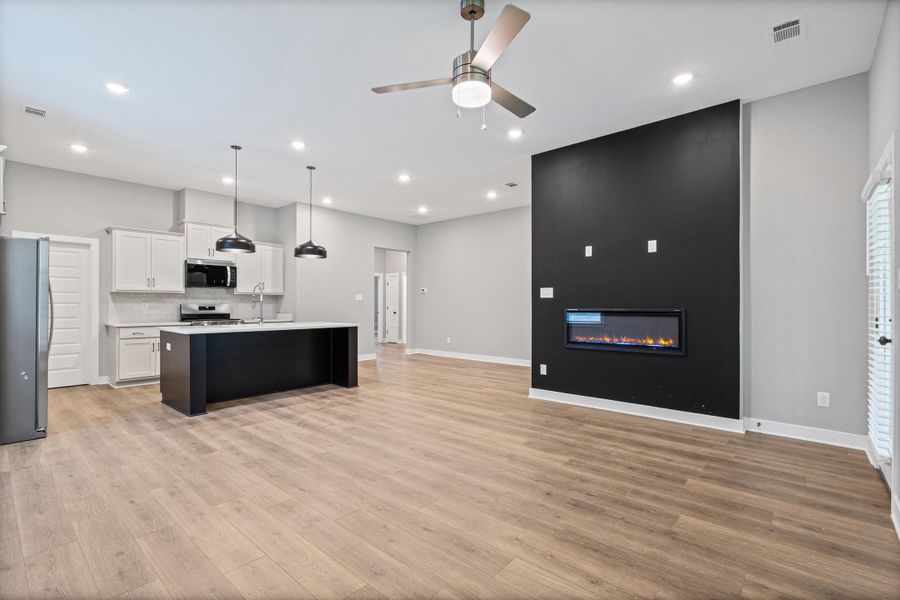 Open-concept living area featuring wood-finish flooring and a contemporary linear fireplace Open-concept living area featuring wood-finish flooring and a contemporary linear fireplace