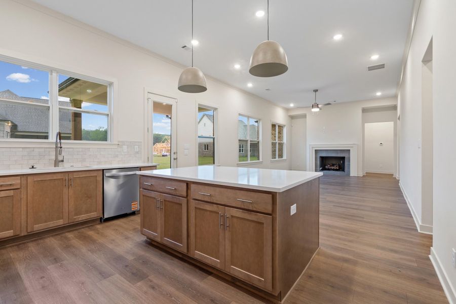 Open-concept interior featuring wood-finish flooring, a kitchen island with a light-colored countertop, and recessed lighting Open-concept interior featuring wood-finish flooring, a kitchen island with a light-colored countertop, and recessed lighting