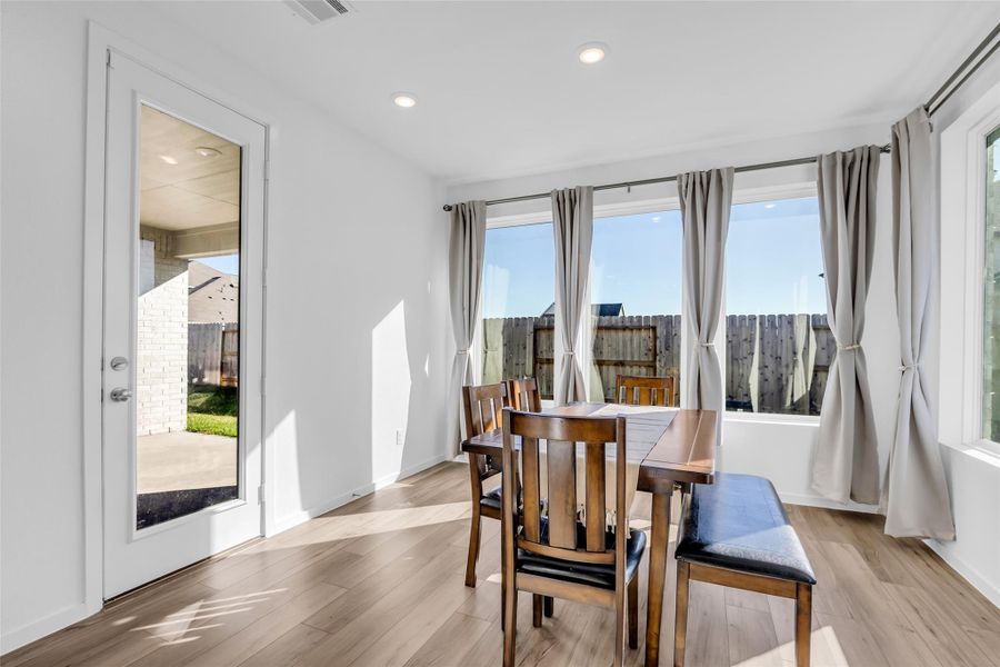 Dining Area: Bright and open with large windows that invite natural light throughout the day. The glass door to the left provides direct access to the covered patio, creating an easy indoor-outdoor flow for everyday living and entertaining. Dining Area: Bright and open with large windows that invite natural light throughout the day. The glass door to the left provides direct access to the covered patio, creating an easy indoor-outdoor flow for everyday living and entertaining.