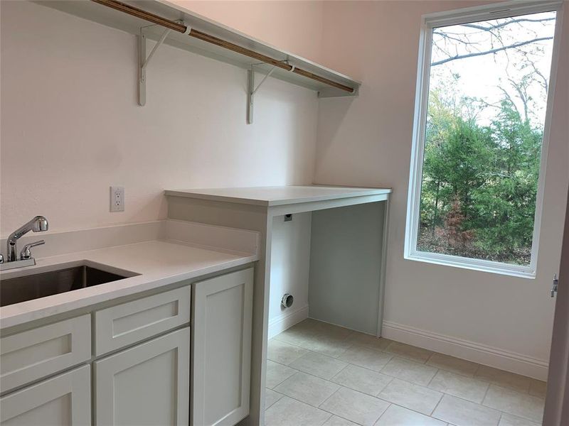 Laundry area with baseboards and light tile patterned floors Laundry area with baseboards and light tile patterned floors