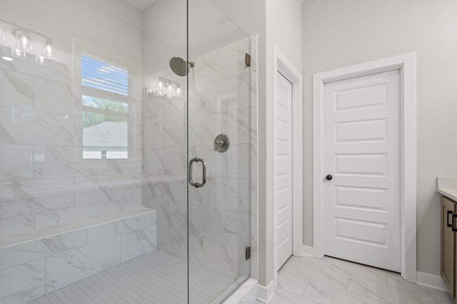 Full bathroom with light marble finish floors, a marble finish shower, and vanity