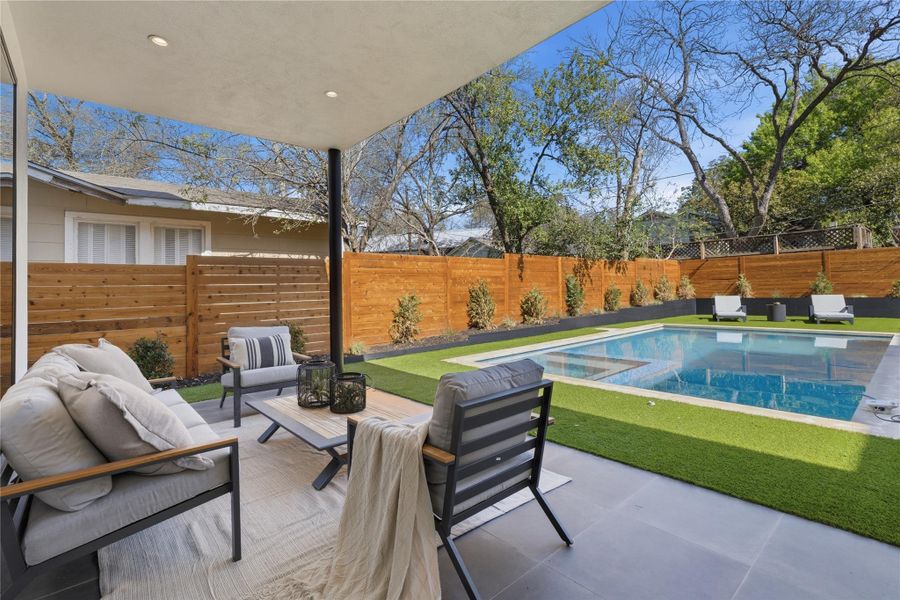 Fenced backyard with an outdoor living space, a patio area, and a pool with connected hot tub