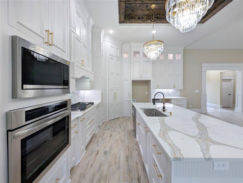 Kitchen with appliances with stainless steel finishes, light stone countertops, recessed lighting, white cabinets, and glass insert cabinets