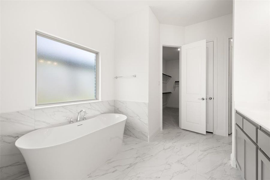Full bathroom with a freestanding bath, vanity, marble finish floors, a closet, and a wainscoted wall Full bathroom with a freestanding bath, vanity, marble finish floors, a closet, and a wainscoted wall