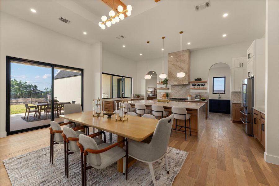 Dining area featuring light wood-style flooring, a high ceiling, healthy amount of natural light, and recessed lighting