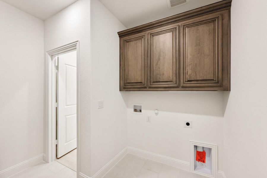 Laundry room with dark wood upper cabinets, washer and dryer hookups, and white walls and tile floor. Laundry room with dark wood upper cabinets, washer and dryer hookups, and white walls and tile floor.