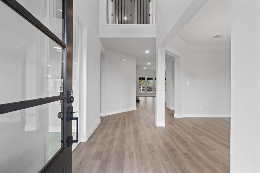An inviting entrance opens up to an open-concept layout, seamlessly connecting the entry to the formal dining room and Great Room with durable laminate flooring and striking architectural details.