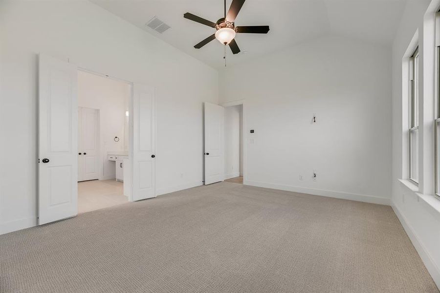 Unfurnished bedroom with light colored carpet, lofted ceiling, and a ceiling fan Unfurnished bedroom with light colored carpet, lofted ceiling, and a ceiling fan