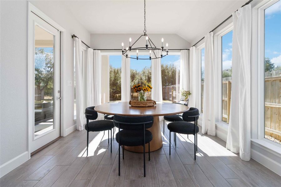 Sunroom featuring plenty of natural light, lofted ceiling, a chandelier, and wood finished floors Sunroom featuring plenty of natural light, lofted ceiling, a chandelier, and wood finished floors