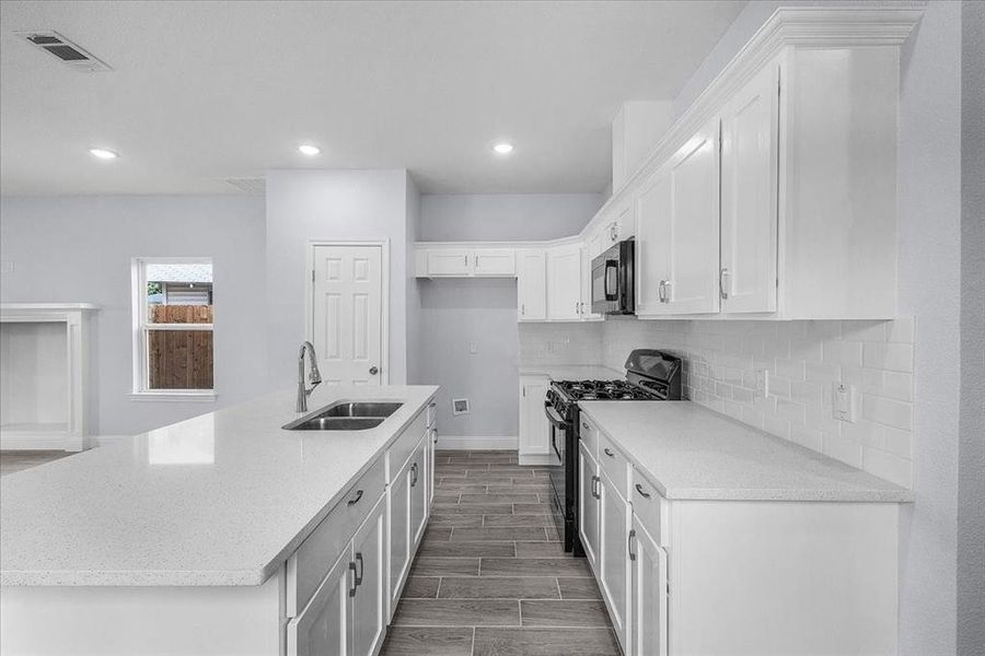 Kitchen featuring black appliances, backsplash, white cabinetry, recessed lighting, and wood finished floors