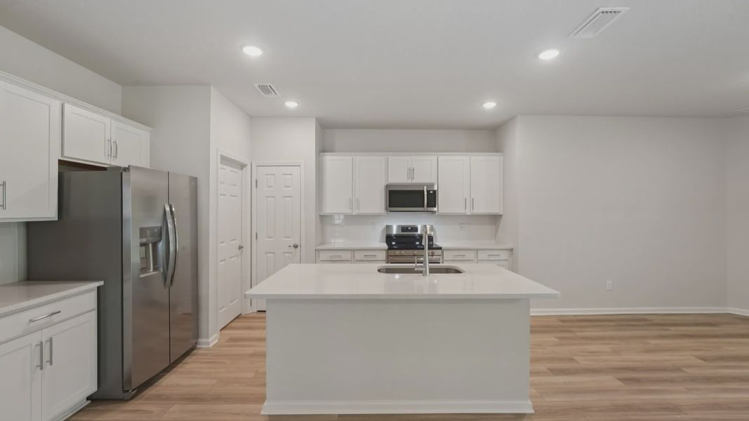 Experience elegance in this Palm Coast kitchen with quartz surfaces, sleek cabinetry, and exquisite wood flooring.
