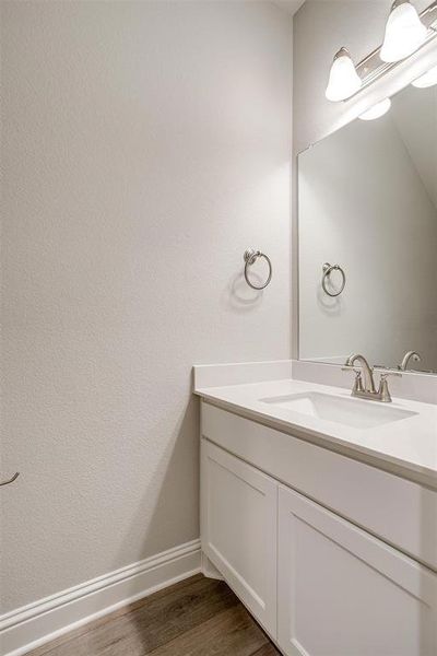 Bathroom featuring vanity, baseboards, and wood finished floors