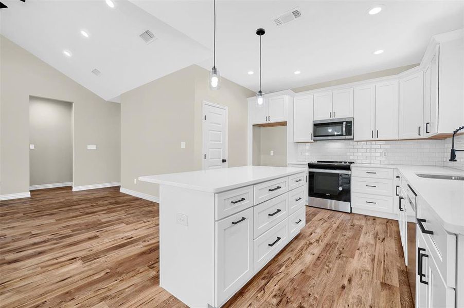 Kitchen featuring sink, a center island, white cabinets, and appliances with stainless steel finishes