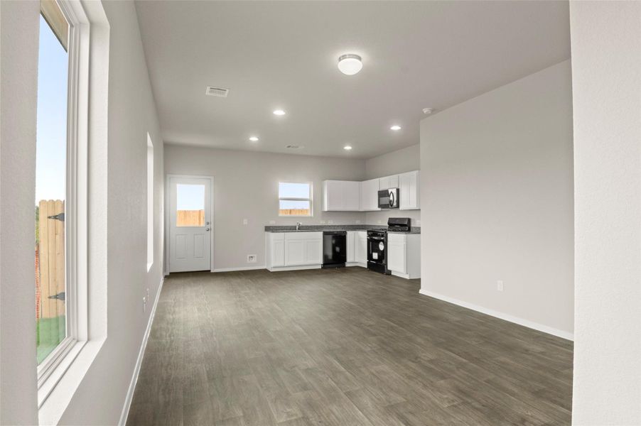 Unfurnished living room featuring dark wood-type flooring and recessed lighting