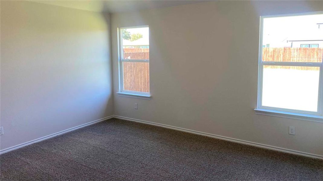 Spare room featuring dark colored carpet and baseboards