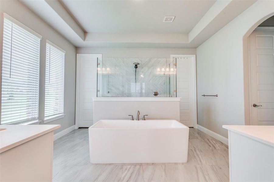 A sleek freestanding tub takes center stage in front of a spacious walk-in shower, creating a luxurious and spa-like focal point in this beautifully designed bathroom.