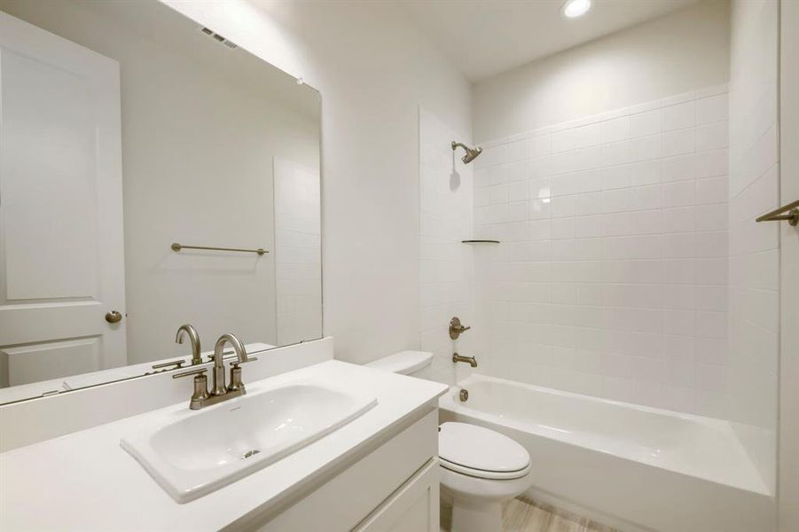 Bright bathroom featuring a contemporary vanity with an integrated sink, brushed nickel faucet, large wall mirror, and a full-size bathtub with subway tile surround Bright bathroom featuring a contemporary vanity with an integrated sink, brushed nickel faucet, large wall mirror, and a full-size bathtub with subway tile surround