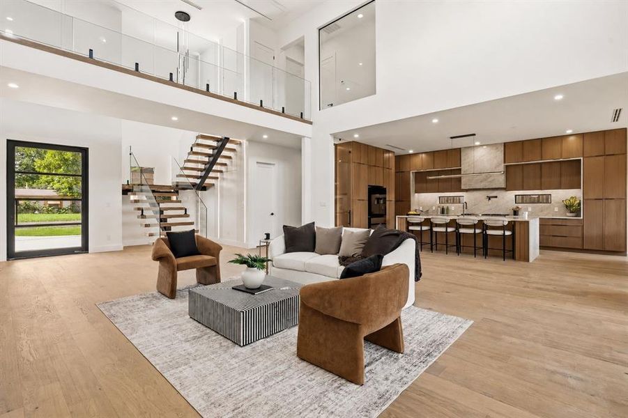 Expansive open-concept living space featuring wood-finish flooring, a two-story ceiling, and a modern kitchen