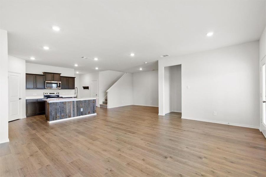Open-concept living space featuring wood-finish flooring, recessed lighting, and a modern kitchen island with integrated lighting
