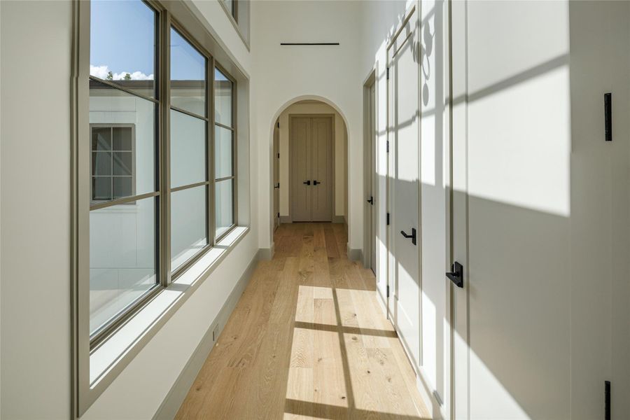 No dark hallways here. Oversized windows line this second-floor passage, casting beautiful natural light across the white oak floors and leading through another signature archway. Even the spaces between the rooms were designed to feel special.