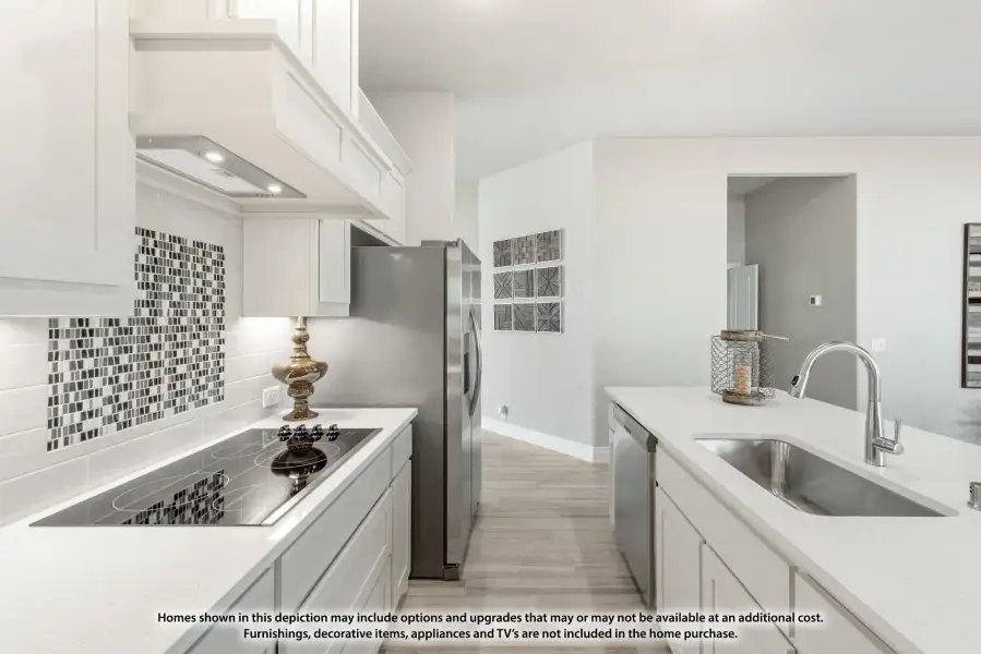 Kitchen with white cabinets, mosaic tile backsplash, stainless appliances, and undermount sink with light wood floors