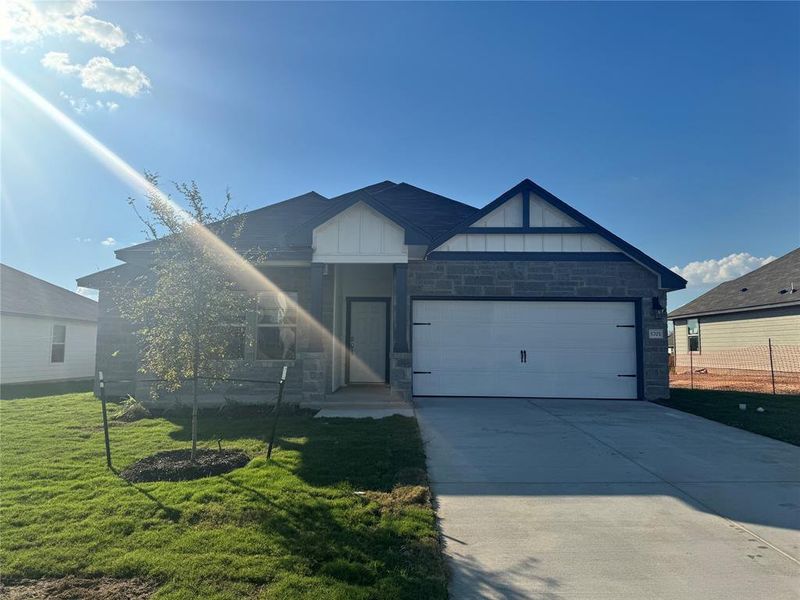View of front of home with stone siding, driveway, a front lawn, and an attached garage View of front of home with stone siding, driveway, a front lawn, and an attached garage