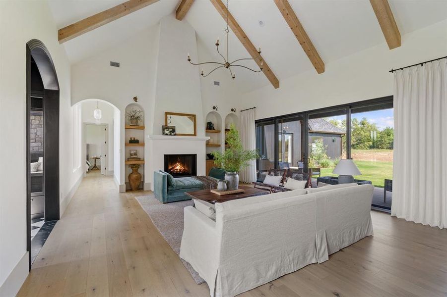 Living room with high vaulted ceiling, beam ceiling, and light hardwood / wood-style flooring