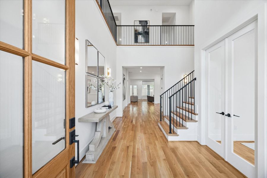Wide plank white oak floors lead through a two story foyer designed for easy circulation and everyday flow. Soaring ceilings, an open railing above, and direct sightlines to the main living areas create a connected layout that feels welcoming from the moment you step inside. Wide plank white oak floors lead through a two story foyer designed for easy circulation and everyday flow. Soaring ceilings, an open railing above, and direct sightlines to the main living areas create a connected layout that feels welcoming from the moment you step inside.