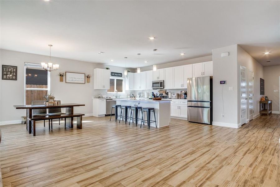 Kitchen with white cabinets, a breakfast bar area, pendant lighting, light wood-style flooring, and recessed lighting