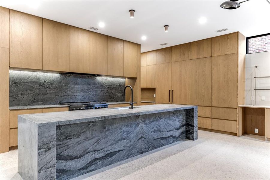 Kitchen featuring Wakanda quartzite countertops and backsplash, custom modern cabinets, exposed aggregate flooring, an island with sink, and recessed lighting