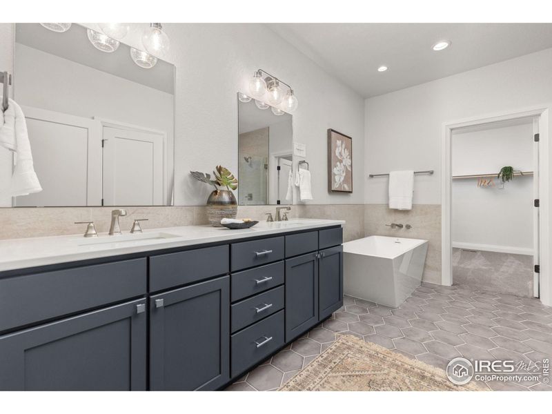 The primary ensuite, including dual vanities, Quartz counters, and porcelain tile flooring, tile, and backsplash