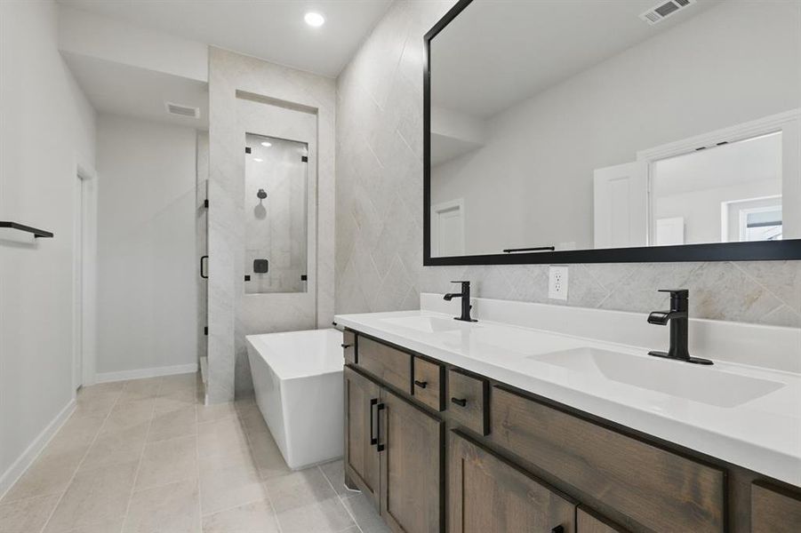 Bathroom with a shower stall, a freestanding tub, double vanity, light tile patterned floors, and tasteful backsplash