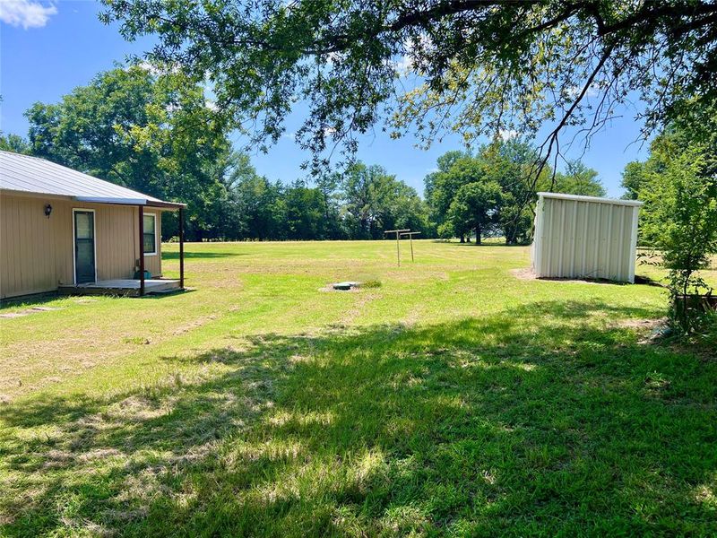 View of green lawn featuring a small storage shed View of green lawn featuring a small storage shed