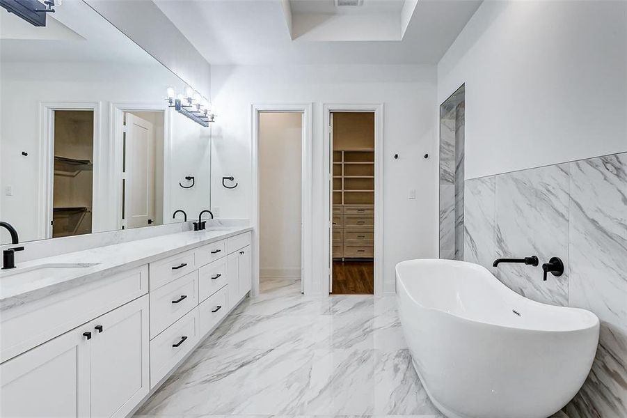 What a stunning ensuite bathroom!  Features include dual vanities, crisp white cabinets with coordinating white countertops, oil rubbed bronze fixtures, a large frameless mirror with vanity lighting, an oversized walk-in shower, soaking tub, linen closet, and privately tucked away commode.