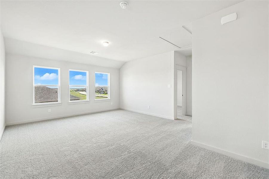 Unfurnished room with light colored carpet, attic access, and lofted ceiling Unfurnished room with light colored carpet, attic access, and lofted ceiling