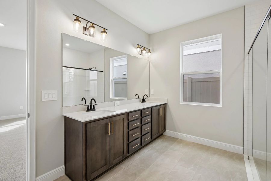 The primary bathroom features a double sink vanity and aspects of AW Collection® Oxford